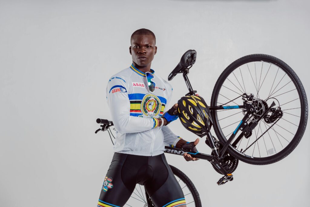 African American cyclist confidently holds a mountain bike indoors, showcasing strength and style.